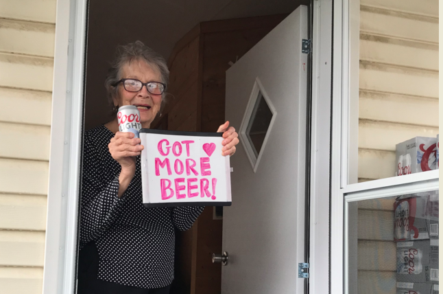 Olive Veronesi celebrates getting a stash of Coors Light with a sign that says, "Got More Beer!"